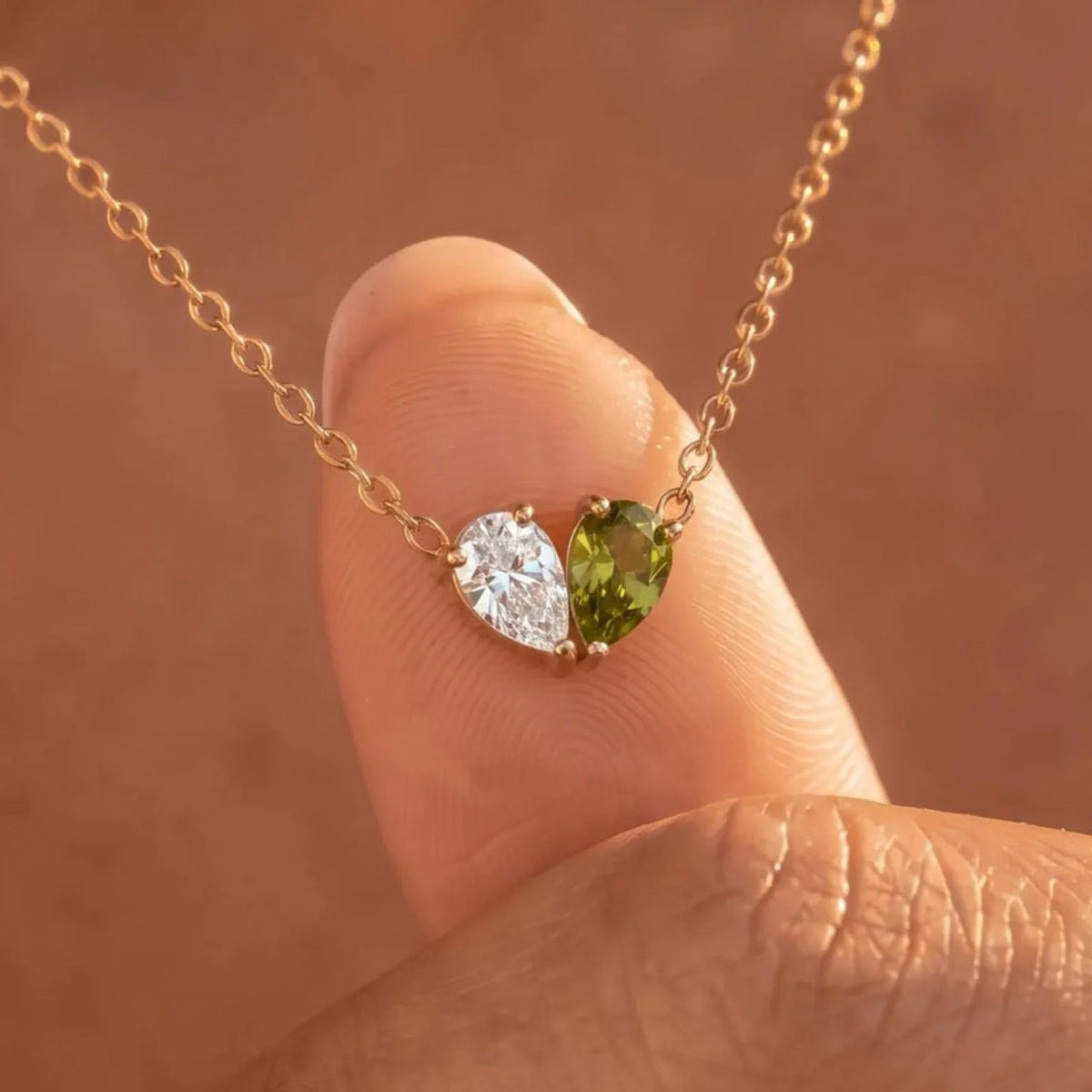 Collier Veria pierre blanche et péridot tenu du bout des doigts